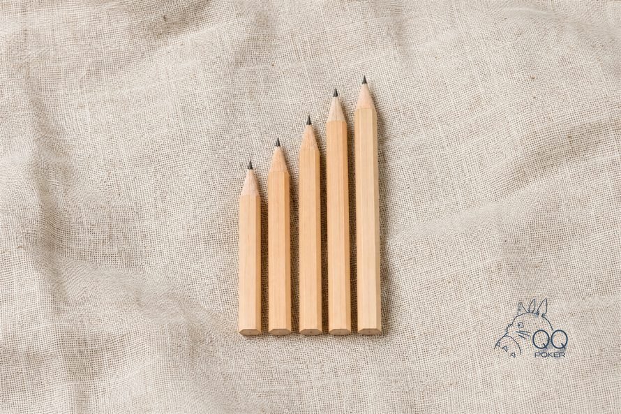 本色亚麻布上五支削好的木铅笔按长短排成阶梯,正俯拍